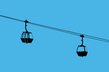 A silhouette of two air-cable cabins
