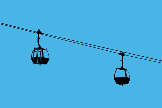 A silhouette of two air-cable cabins