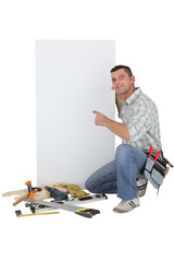 Handyman pointing to a blank sign