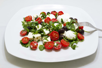 Insalata con rucola, feta, olive nere, mozzarella e pomodorini
