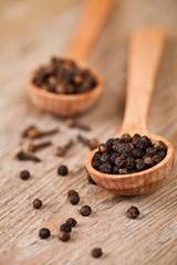 black pepper and cloves in wooden spoons