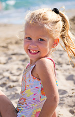 Девочка сидит на песке у моря