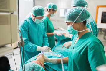 Nurse holding an oxygen mask on a patient undergoing an operatio