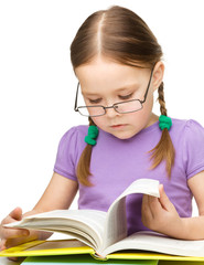 Cute little girl reading book wearing glasses