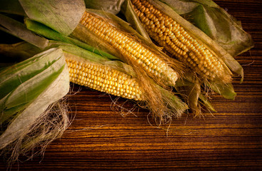 Ripe corn on a dark wooden table with grunge texture