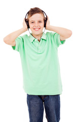 Happy young boy listening to music on headphones against white b