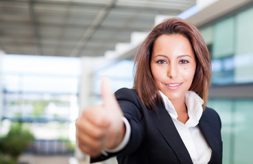 Smiling young businesswoman giving thumbs up