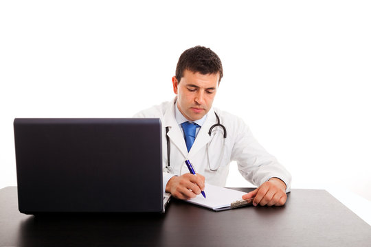Young doctor writing notes in a notebook at the desk, isolated o