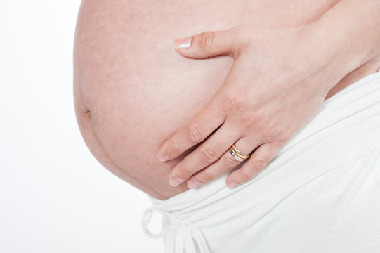 belly of pregnant woman with hands on the breast on white backgr