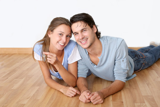 Cheerful couple laying down wooden floor