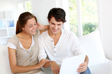 Happy young couple using laptop computer at home