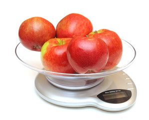 kitchen scales with red apples on white background