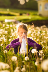 Mädchen auf Wiese mit Pusteblumen und Allergie
