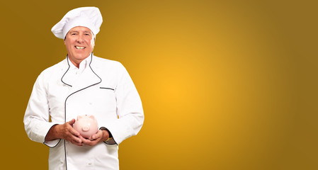 Portrait Of A Chef Holding Piggy Bank