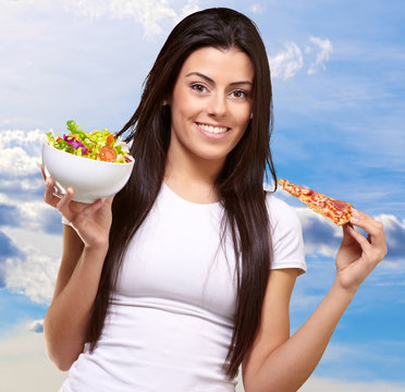 Female Holding A Piece Of Pizza And Salad Bowl