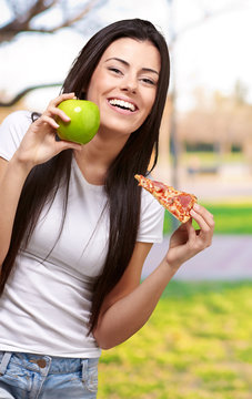Female Holding A Piece Of Pizza And A Apple