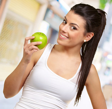 Young woman holding and eating an apple
