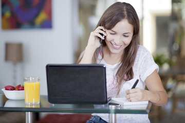 Obraz premium Happy woman working at home and talking to a customer