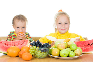Fototapeta na wymiar Two children eat fruit at a table