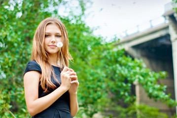 Fototapeta premium A girl with a dandelion in hands