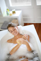 Beautiful woman using bath sponge