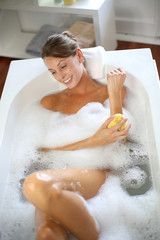 Beautiful woman using bath sponge