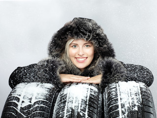 Pretty woman with winter coat behind snowy winter tyres