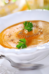 Pumpkin soup with orange juice in white plate, soft focus.