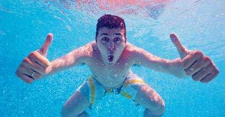 Underwater portrait of happy man in swimming pool.