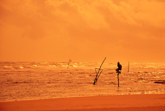 Lone fisherman in the ocean at sunset background in Sri Lanka.