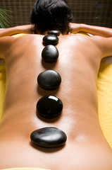 Adult woman getting hot stone massage in spa