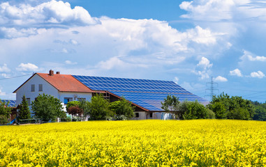 Bauernhof mit Solarzellen im Rapsfeld