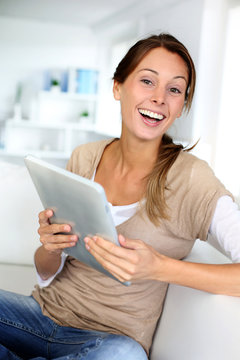 Young woman using electronic tablet sitting on sofa