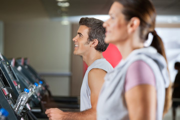 Fototapeta na wymiar Man And Woman Running On Treadmill