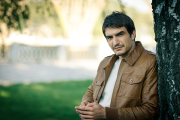 Portrait of handsome man outdoors in brown leather jacket
