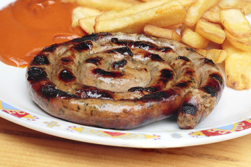 Fried potatoes with grilled sausages on plate. All in focus.