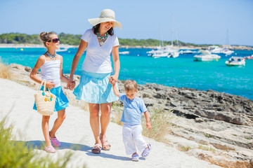 Family of three walking along tropical beach