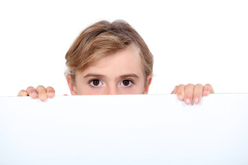 Girl peering over white sign