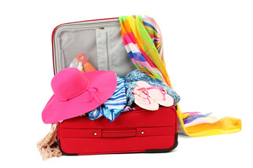 Suitcase with summer clothes, a hat and suntan isolated on