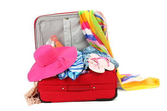 Suitcase with summer clothes, a hat and suntan isolated on