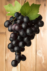 red grapes with leaves on wooden background
