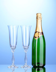Bottle of champagne and goblets on blue background