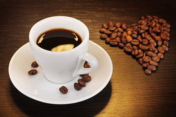 Cup of coffee on wooden table on brown background