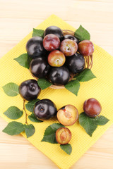 Rip plums on basket on wooden table