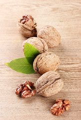 walnuts with green leaves, on wooden background