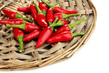 little hot peppers on wicker mat isolated on white