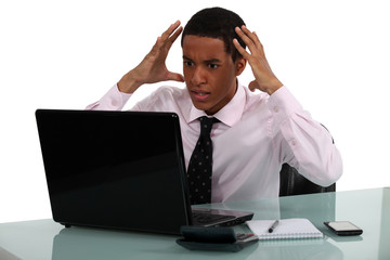 Frustrated young businessman being driven crazy by his computer