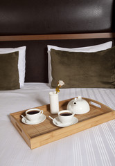 Fototapeta na wymiar Taca z kawy na łóżku w pokoju hotelowym