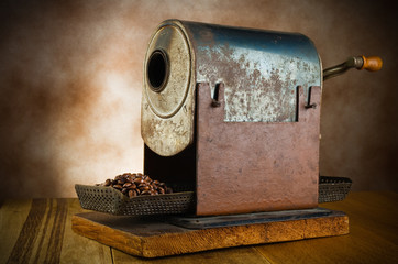 vintage roaster with coffee beans in the wood table