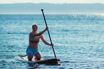 Woman kneeling on Stand Up Paddle Board